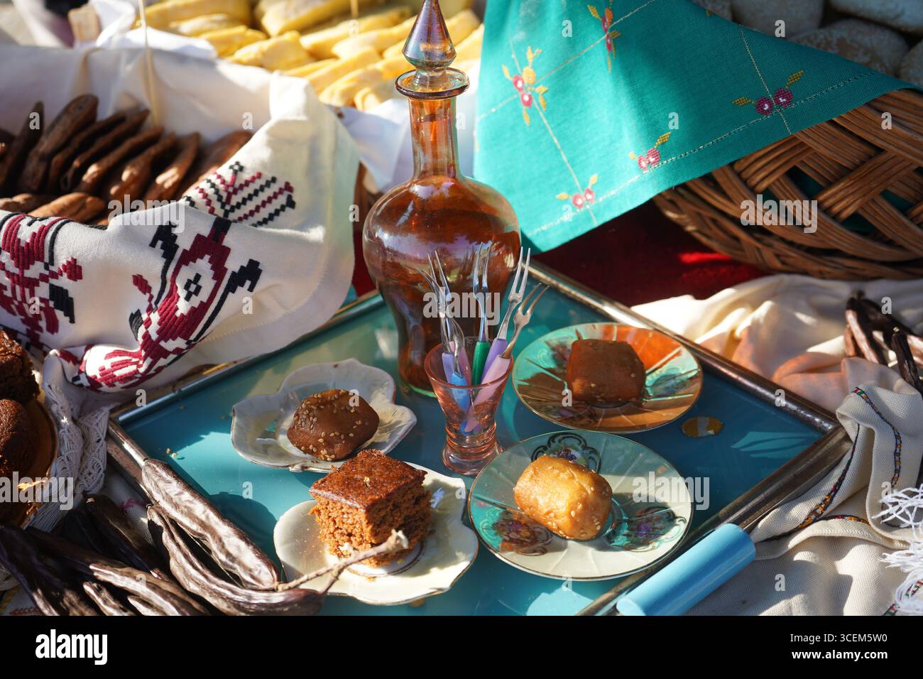 A rustic Cretan feast featuring carob bread, 'rakomelo', and various traditional homemade sweets. The shot is rich with textures and colors. Stock Photo
