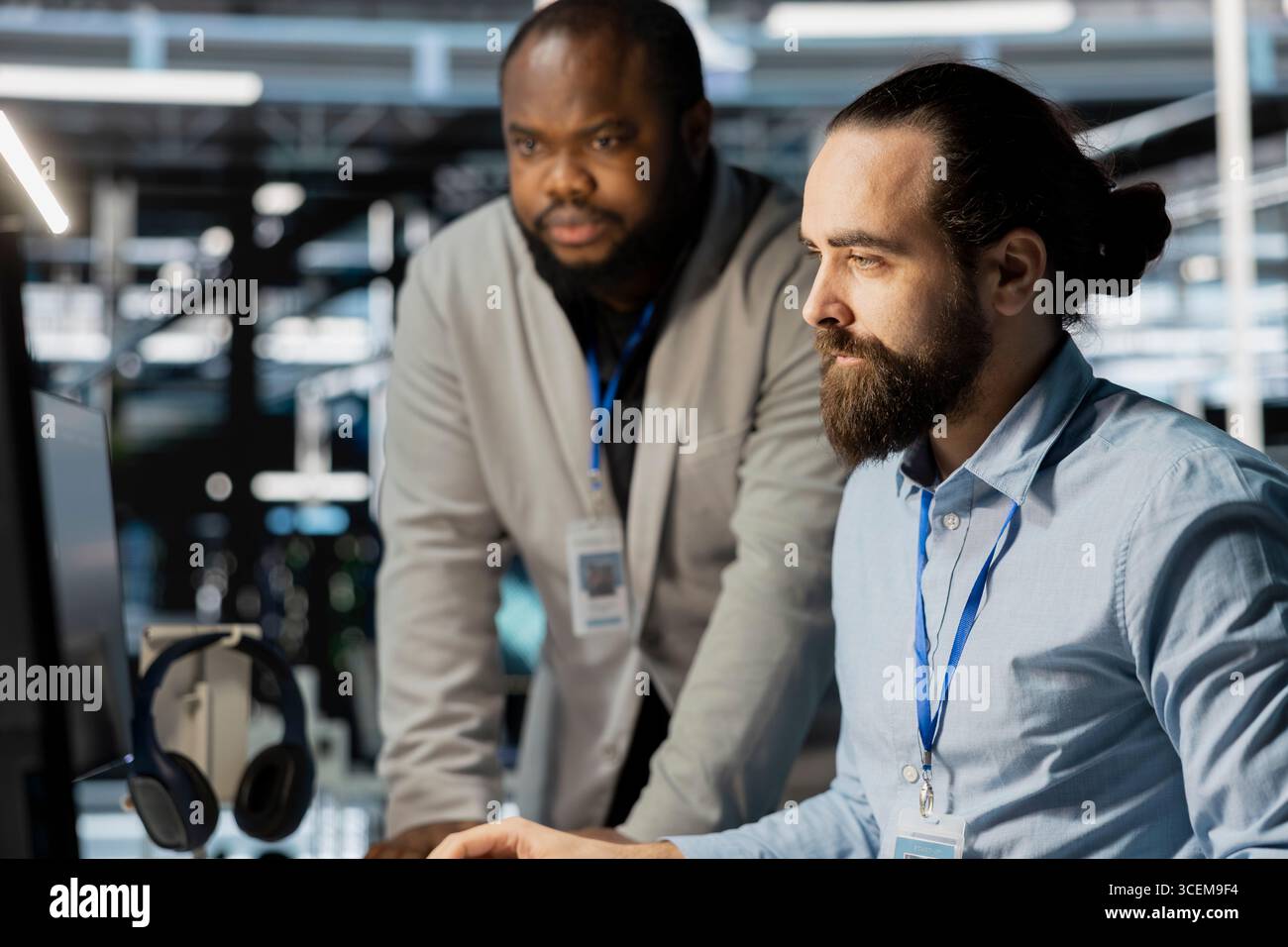 Team of technicians in data center using PC to update storage arrays software, configuring network virtualization. Teamworking colleagues in server room using computer to verify settings Stock Photo
