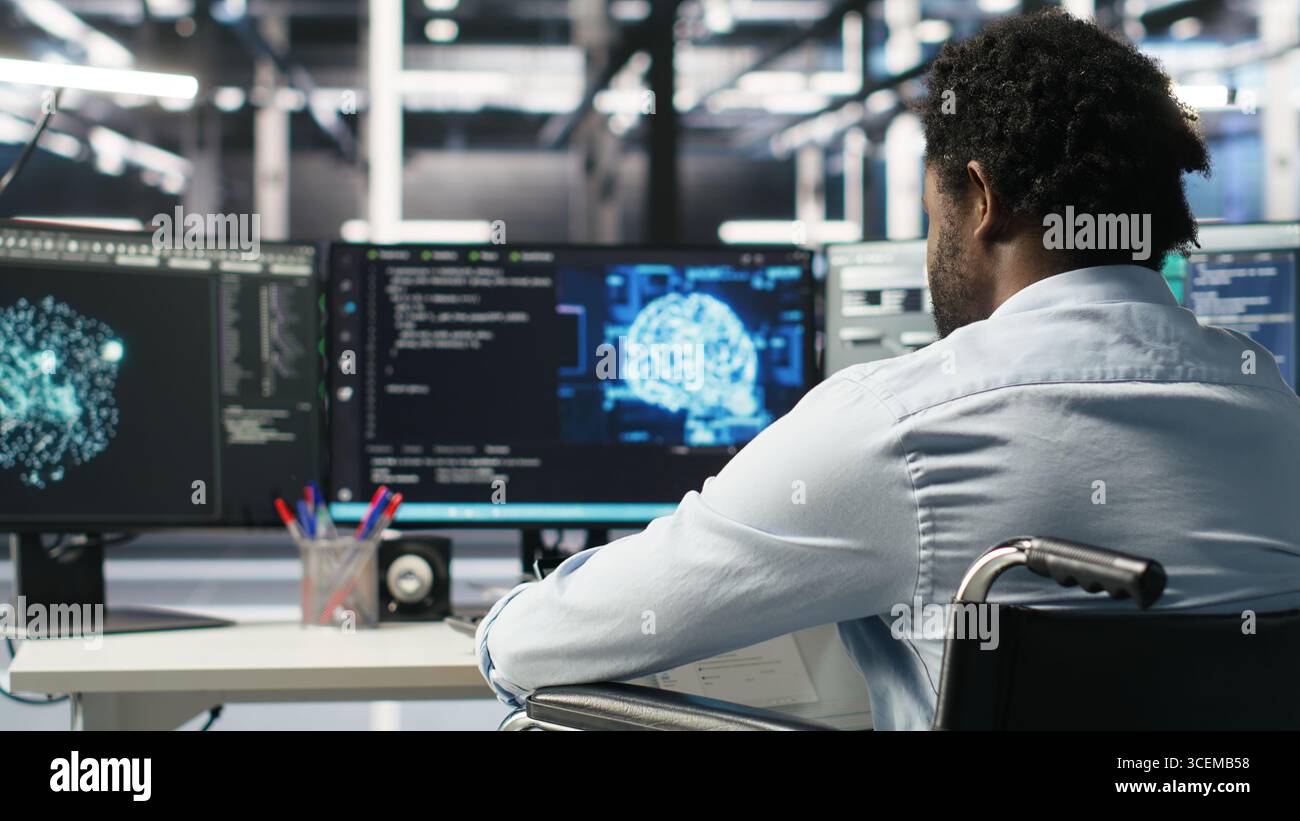 Server room programmer with paraplegia interprets AI generated data analytics graphs. Man in wheelchair using artificial intelligence program showing predictive system metrics in data center, camera B Stock Photo