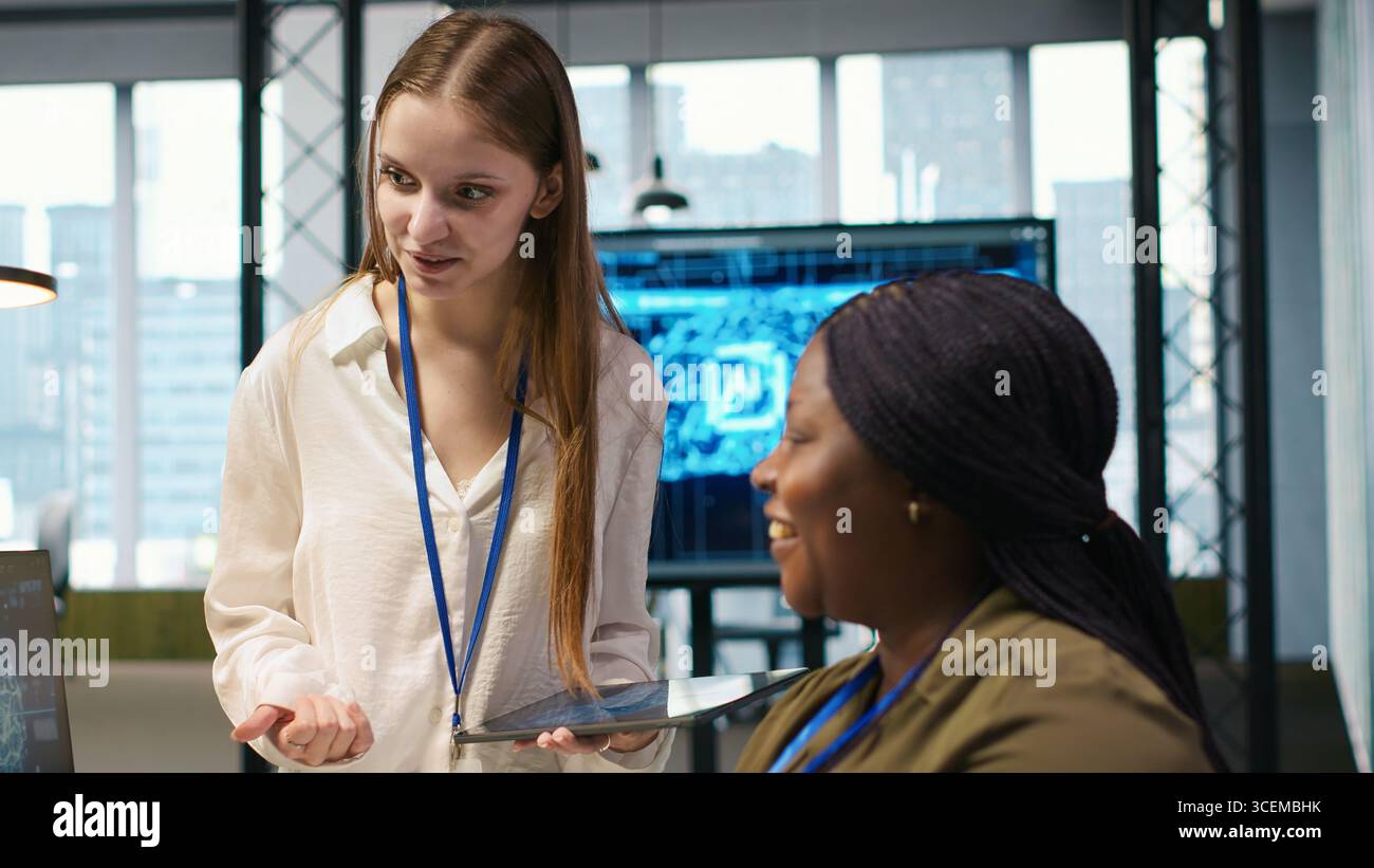 Manager teaching young technician how to develop software and optimize code using AI. Team leader guiding intern in office on how to use artificial intelligence to resolve bottlenecks, camera A Stock Photo