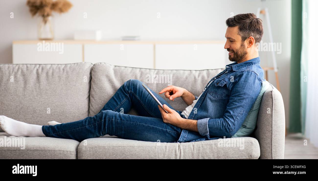 Relaxed bearded man using digital tablet at home Stock Photo