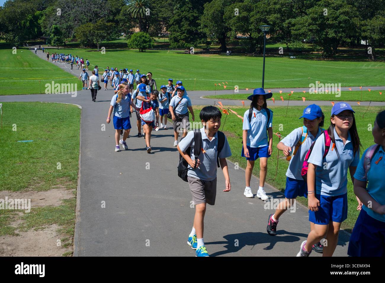Group of school children wearing blue uniforms with sun hats walking on ...