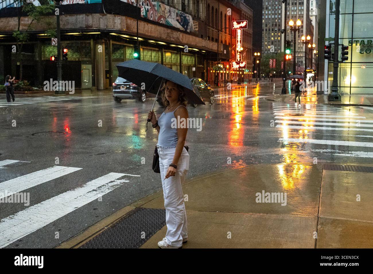 A woman uses an umbrella for protection from rain in The Loop as a ...