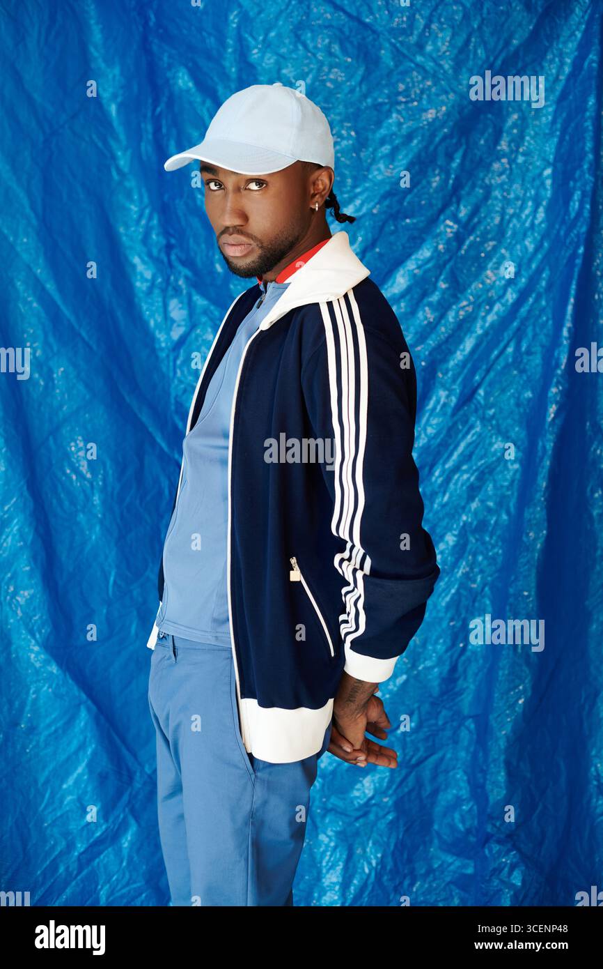 Young man showcases his charm against a vibrant blue backdrop, exuding ...