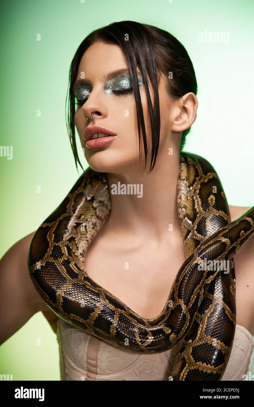 A striking moment as a young beautiful woman poses gracefully with a snake draped around her neck. Stock Photo