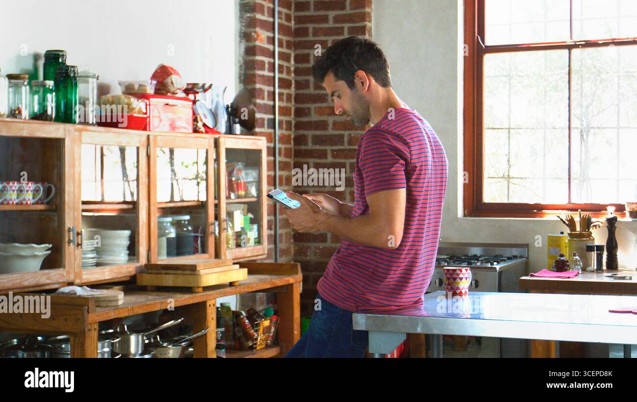 Young Man Using Digital Tablet In Open Plan Apartment Kitchen Stock Photo
