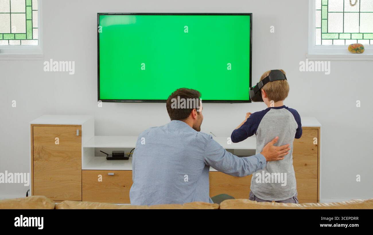 Father And Son Play Computer Game Using Virtual Reality Headset Stock Photo