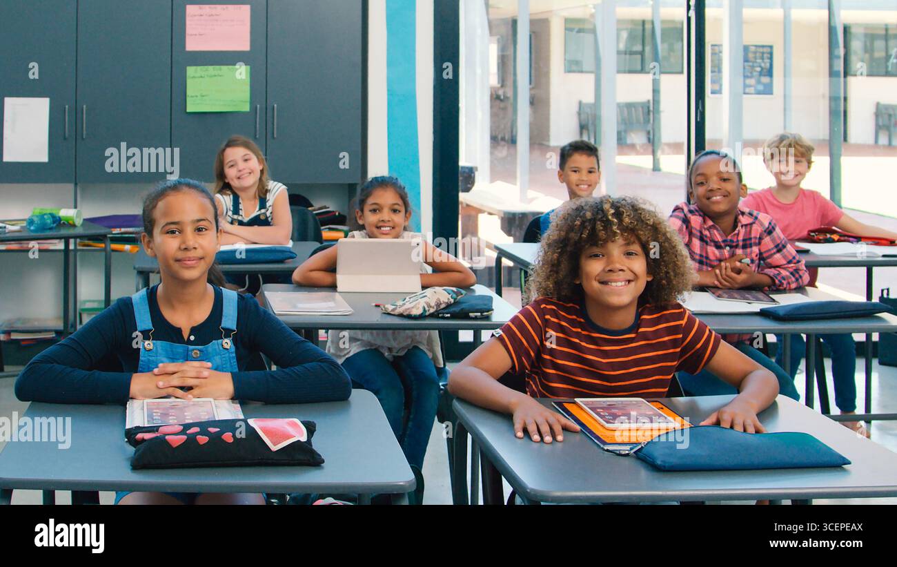 Portrait Of Smiling High School Class Using Digital Tablets In Class Stock Photo