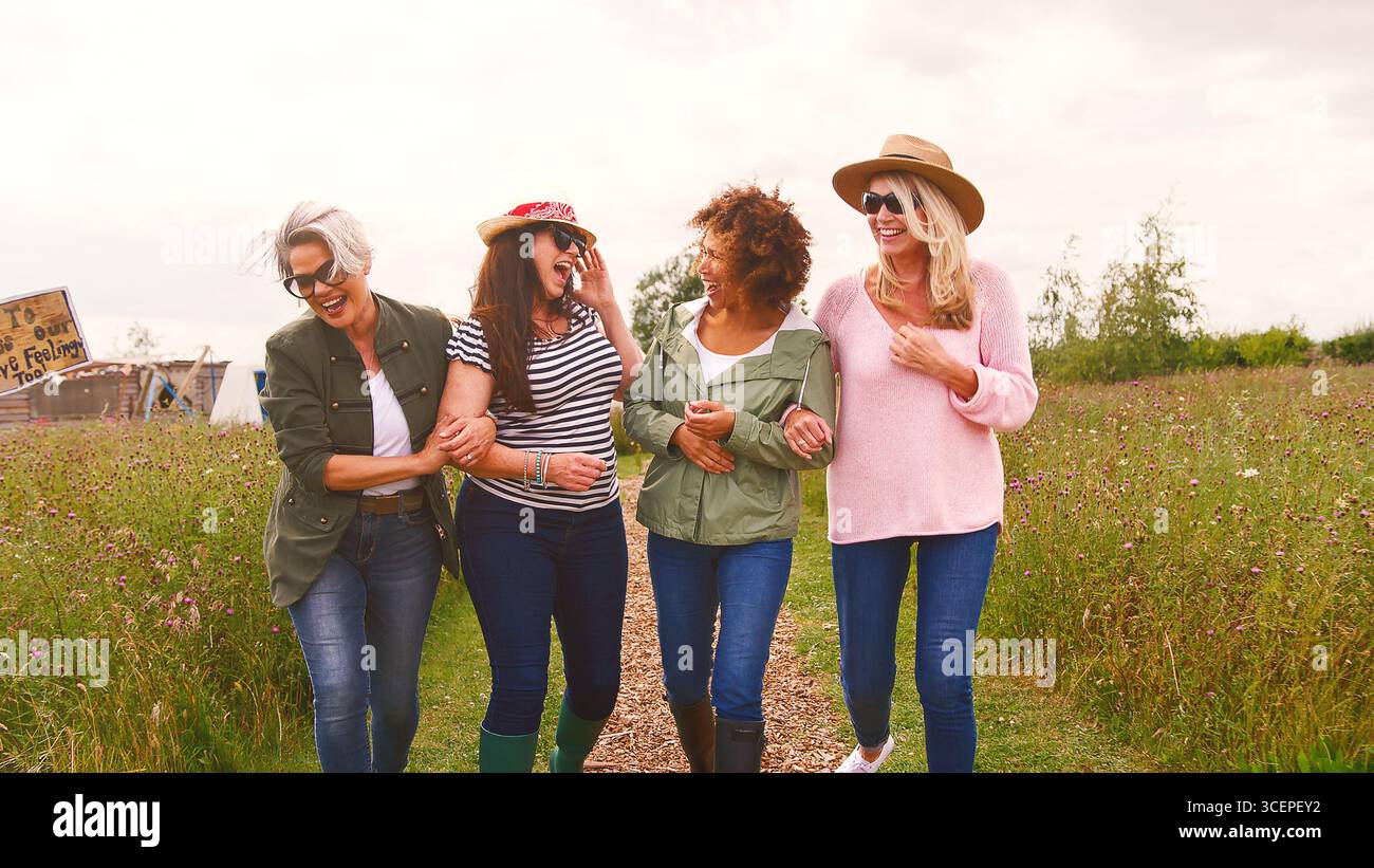 Group Of Smiling Mature Female Friends Walking Arm In Arm Along Path ...