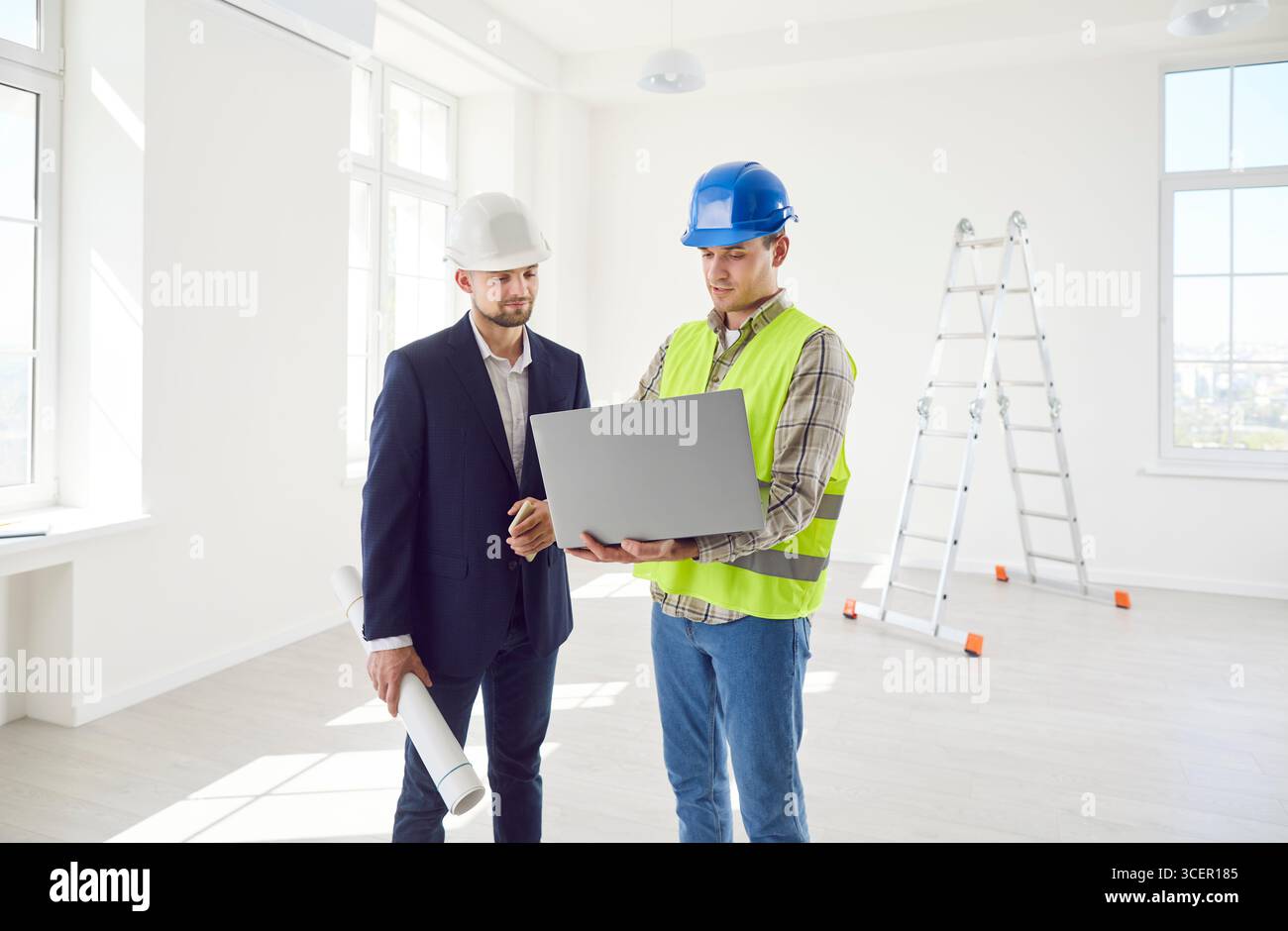 Construction engineer, architect colleague looking at project online on laptop, blueprints, planning Stock Photo