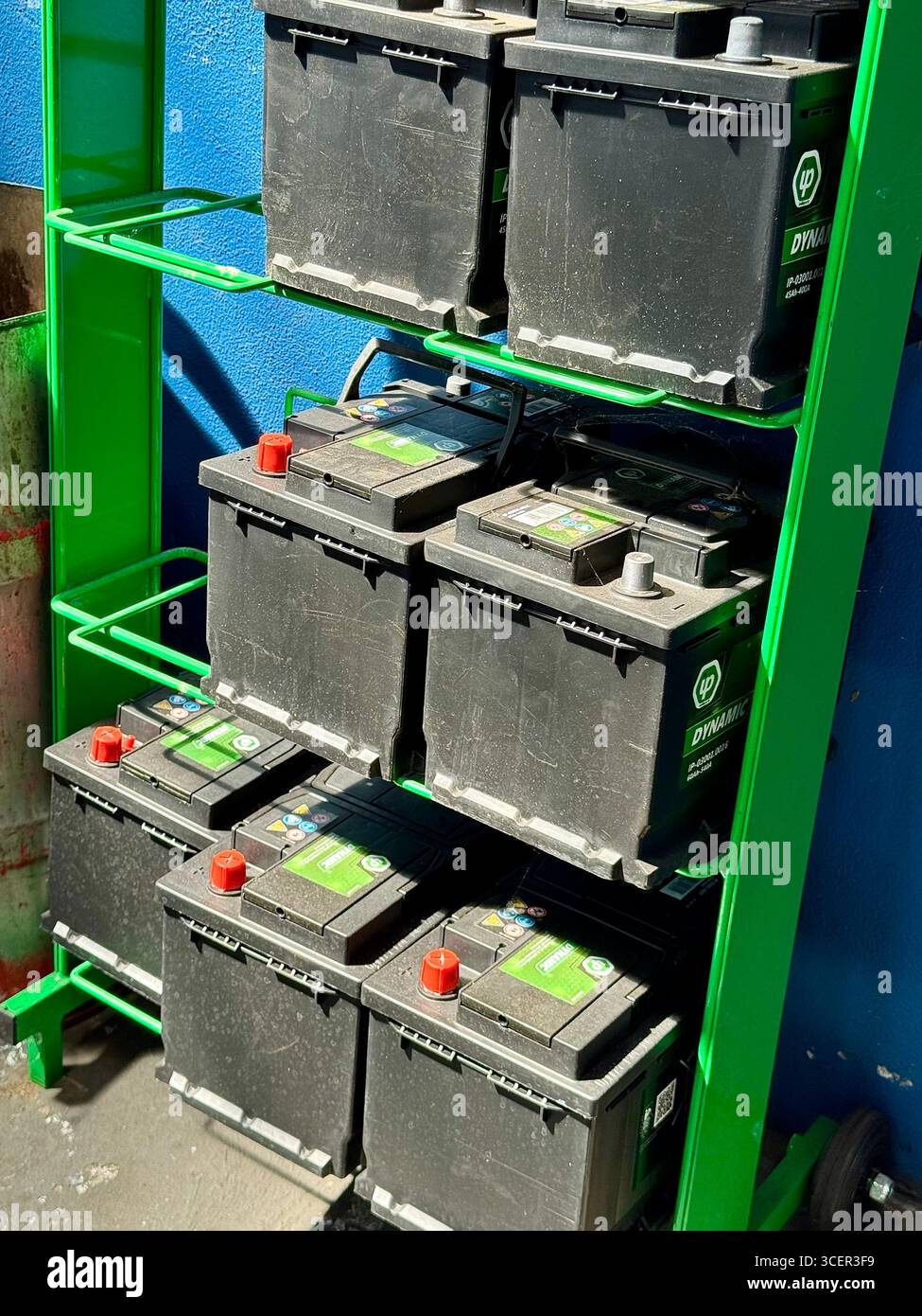 Car batteries displayed on a green metal rack in an automotive workshop. - Smartphone Captured Stock Image