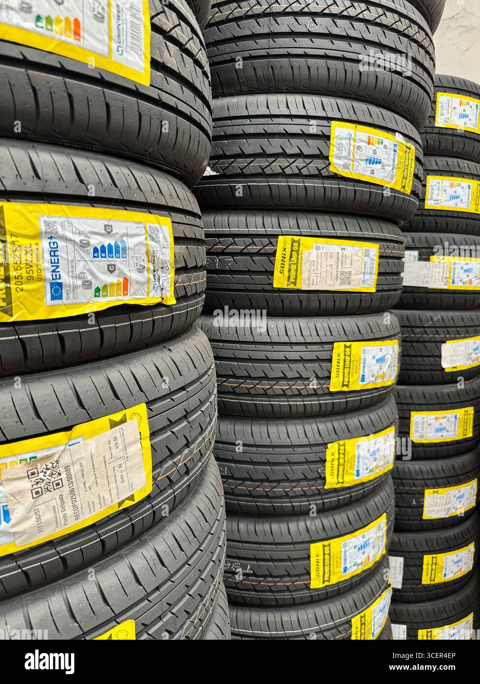 Stacked new car tires in a shop display, showing rubber treads and labels for automotive use. - Smartphone Captured Stock Image