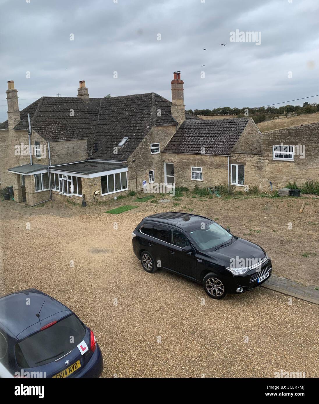 Car village street learner driver L plate road path weather outside view big large small hamlet County Northampton place chimney stacks stack UK - Smartphone Captured Stock Image
