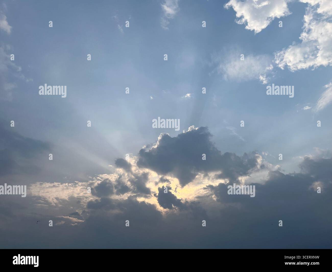 sunlight shining trough fluffy clouds in afternoon - Smartphone Captured Stock Image