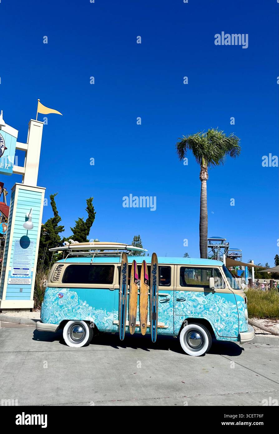 A retro Volkswagen camper van decorated with a surf-inspired design, parked with surfboards attached to the side at a beachside attraction, California - Smartphone Captured Stock Image