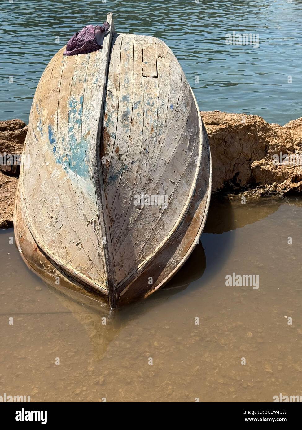 Old rustic overturned wooden boat on the water's edge, vintage marine scene, summer lake or river shore, abandoned boat for fishing, outdoor travel co - Smartphone Captured Stock Image