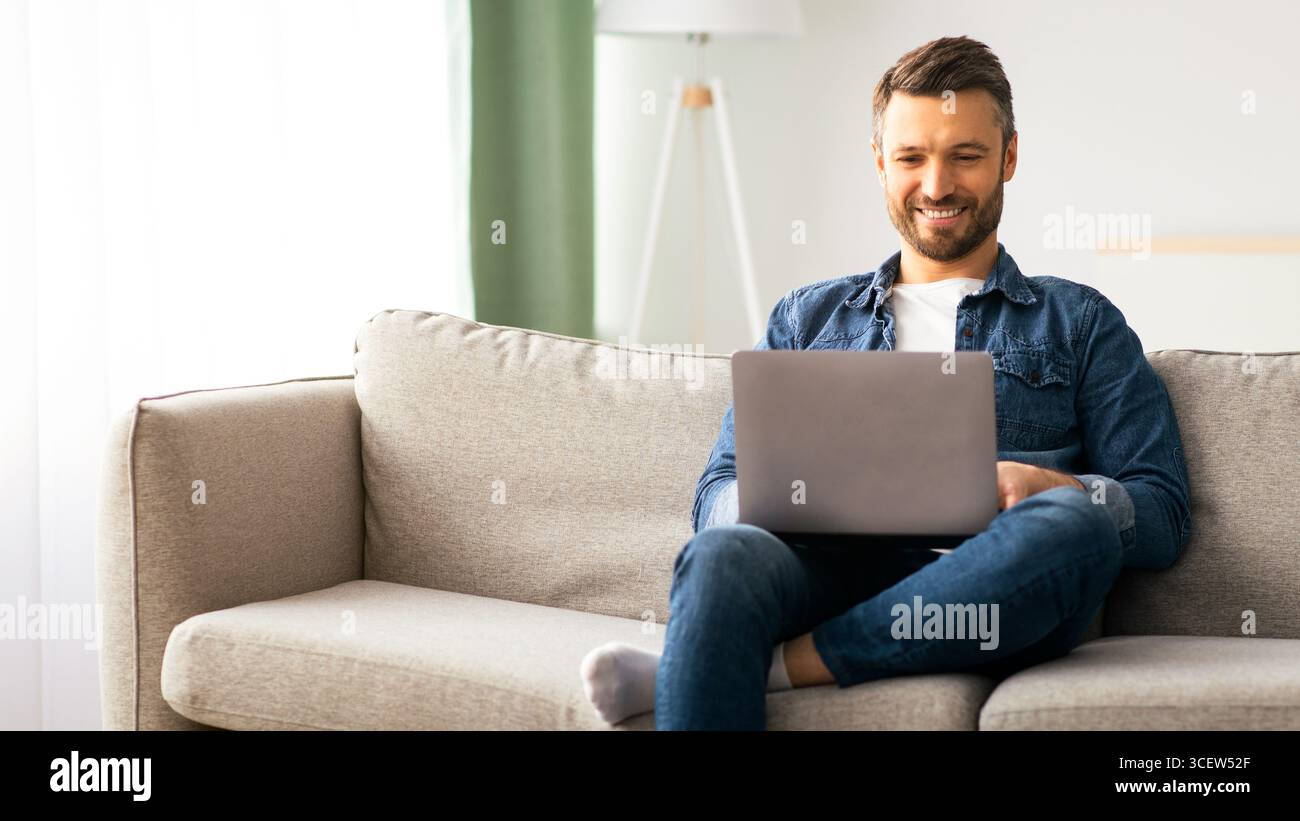 Handsome bearded man using laptop and smiling Stock Photo