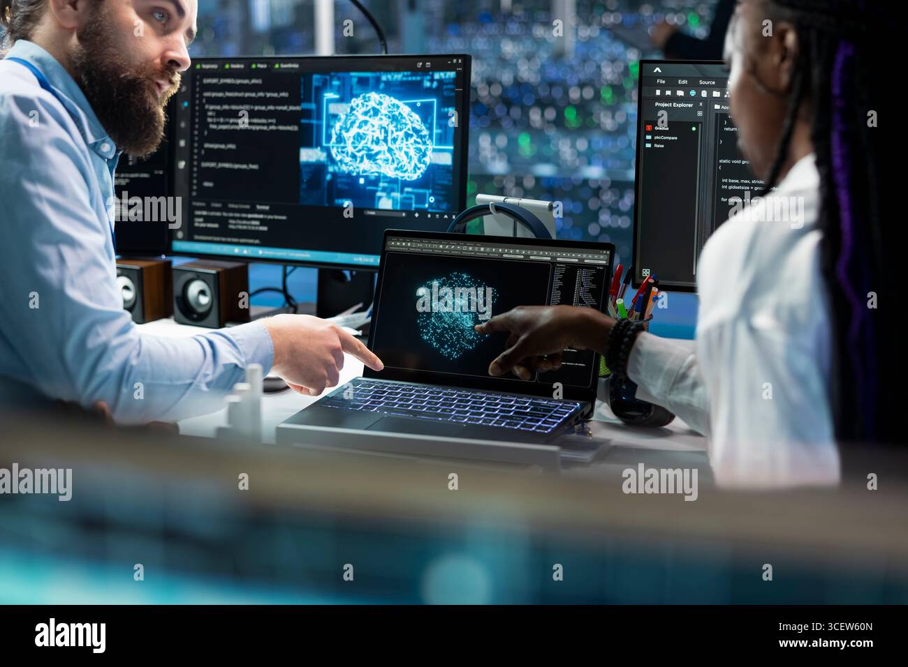 Team leader teaching intern to code in data center, updating AI automation scripts. Server room supervisor guiding trainee during internship, programming artificial intelligence algorithms Stock Photo