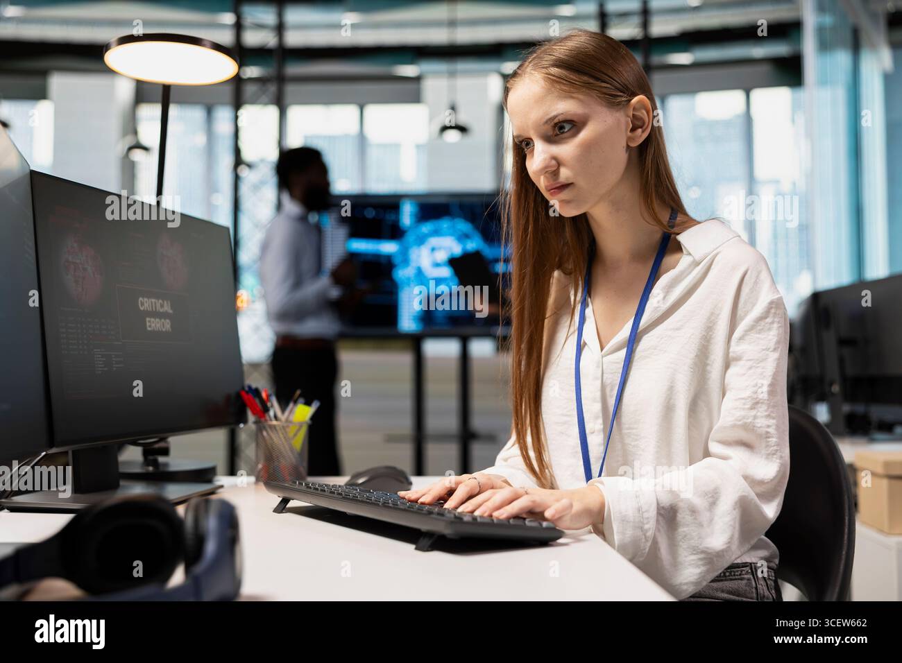 Female technician seeing critical error warning popup while adjusting deep learning algorithms parameters at work. Young worker receiving glitch failure alert while working with AI Stock Photo