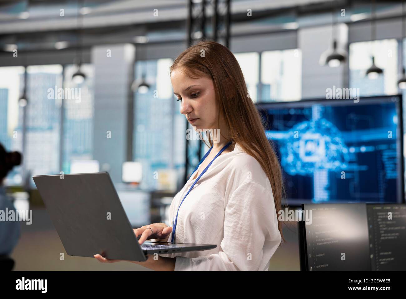 Junior dev in office using AI automation scripts to reduce repetitive coding tasks. Young female software developer using artificial intelligence technology in startup workspace Stock Photo