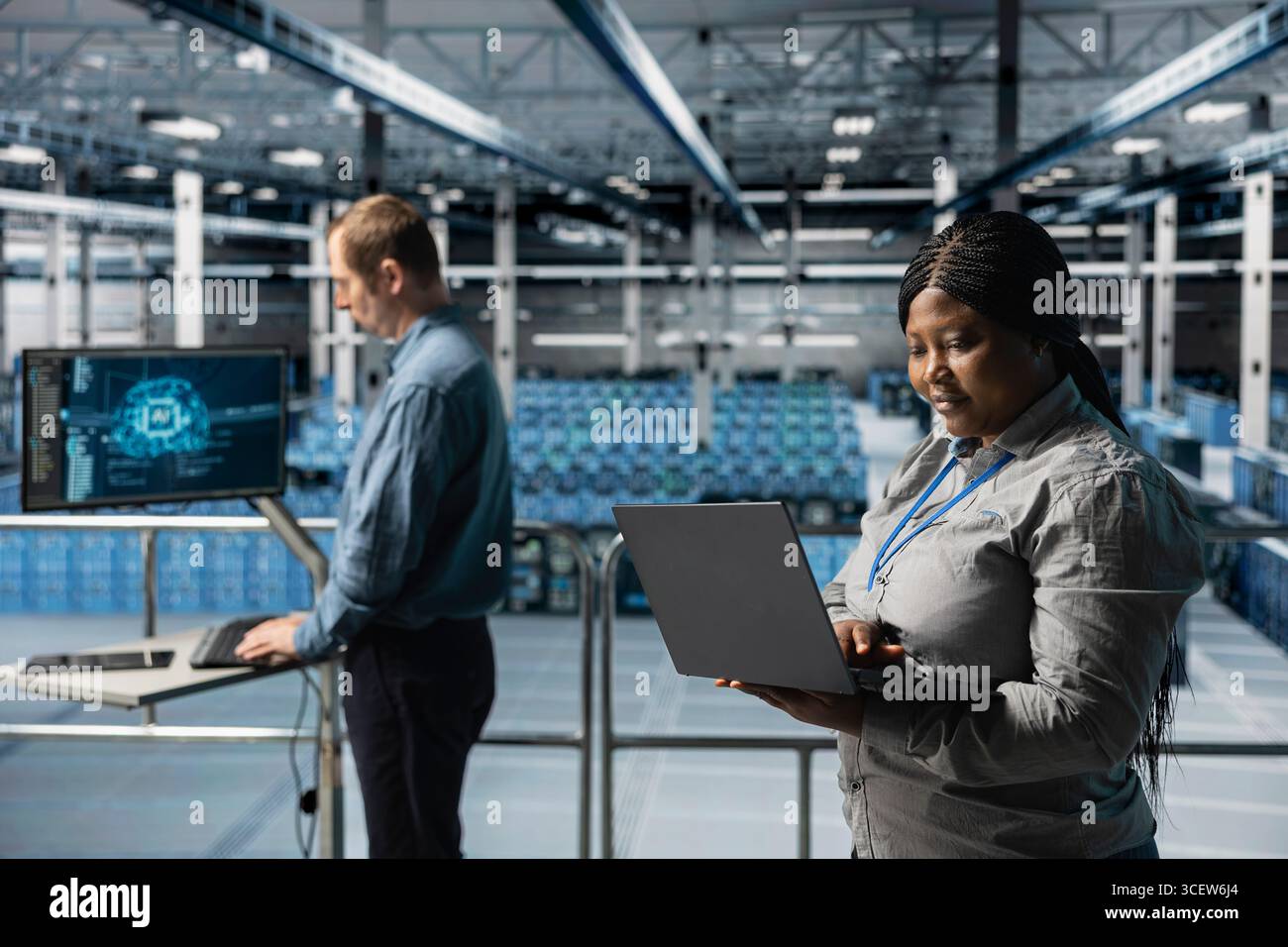 Server farm teamworking admins using laptop to do infrastructure AI machine learning automatization. Data center software developers doing maintenance using artificial intelligence Stock Photo
