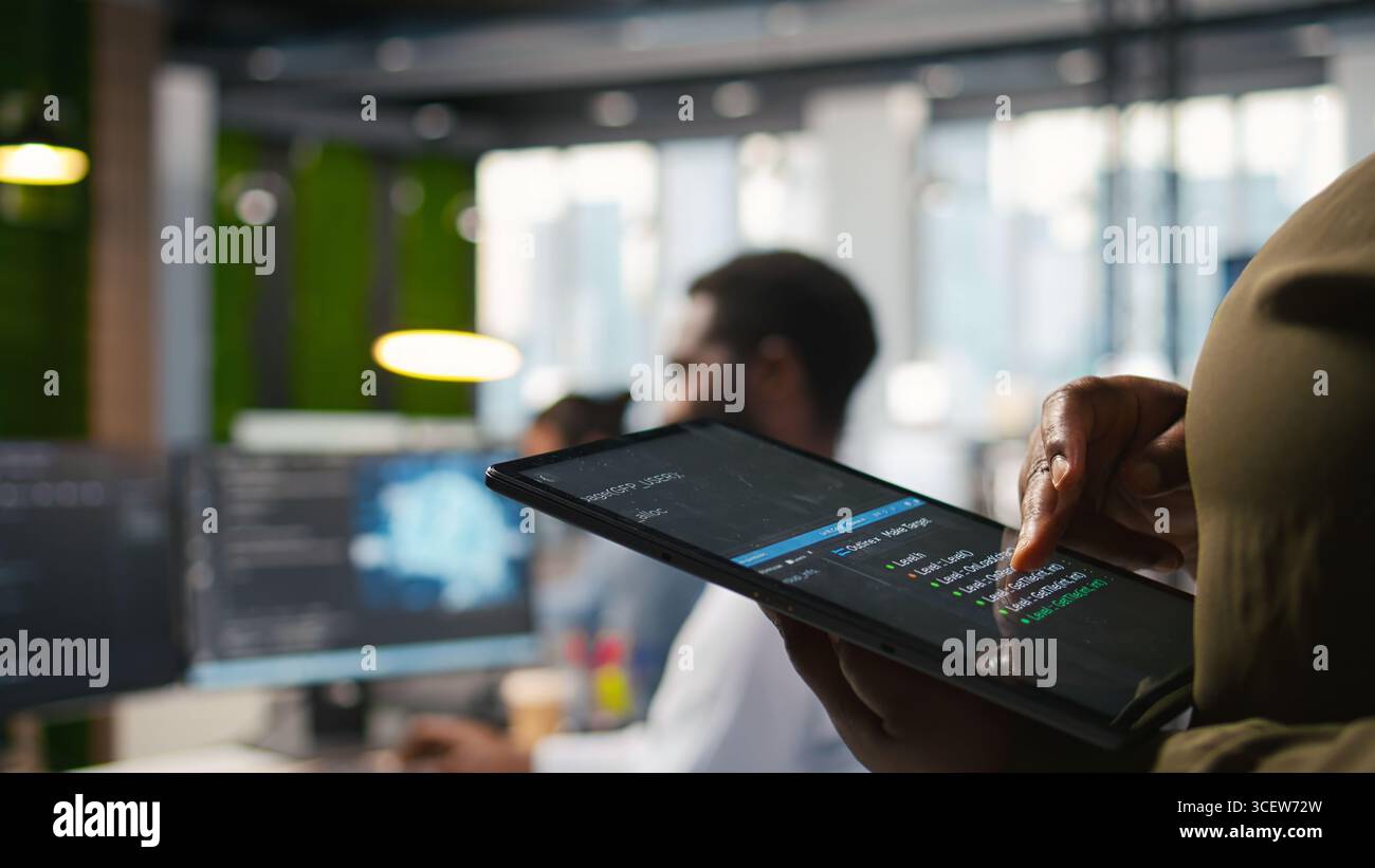 Close up of programmer utilizing AI on tablet to optimize performance and forecast issues. System administrator in office training machine learning models using device, camera A Stock Photo