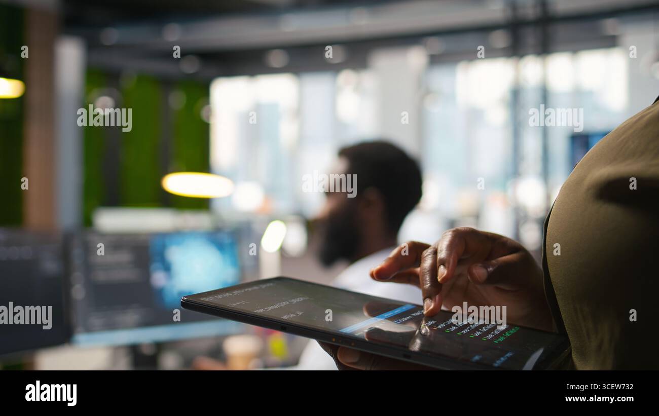 Close up of engineer using tablet to write code, developing machine learning APIs. IT professional troubleshooting software errors and faults using artificial intelligence, camera A Stock Photo