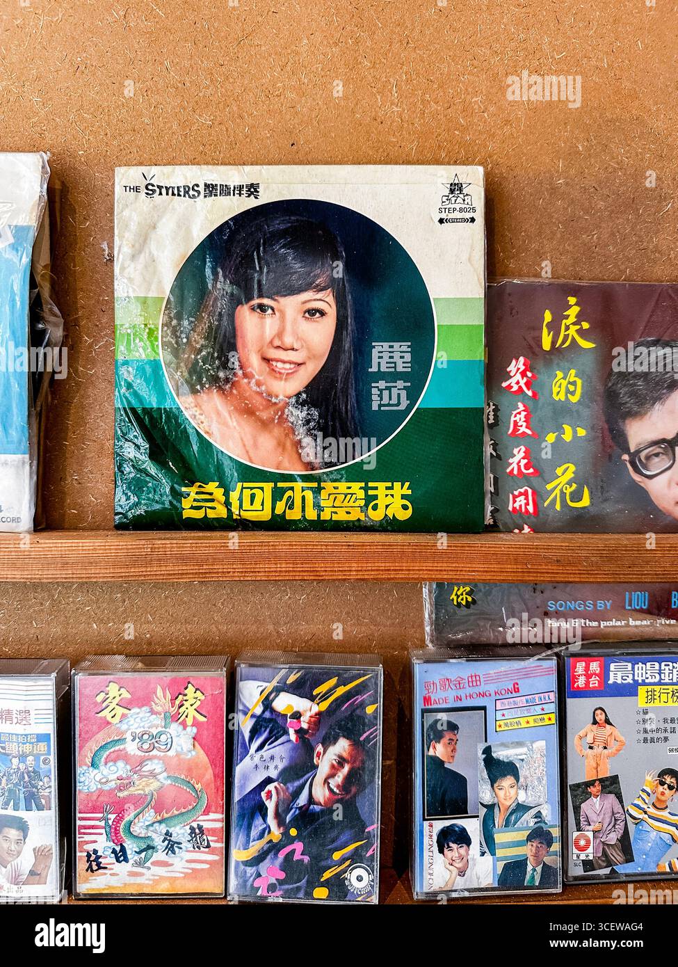 A vintage music shop display featuring retro chinese Asian vinyl records and cassette tapes on wooden shelves in a nostalgic setting Malacca malaysia - Smartphone Captured Stock Image