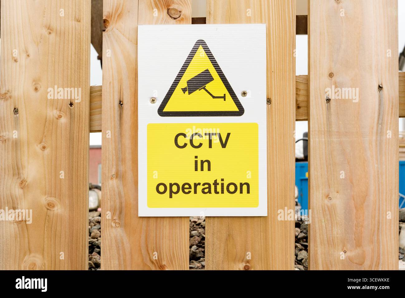 A clear warning sign indicating CCTV in operation is mounted on a wooden fence, promoting safety and vigilance in the surrounding area. Perfect for se Stock Photo