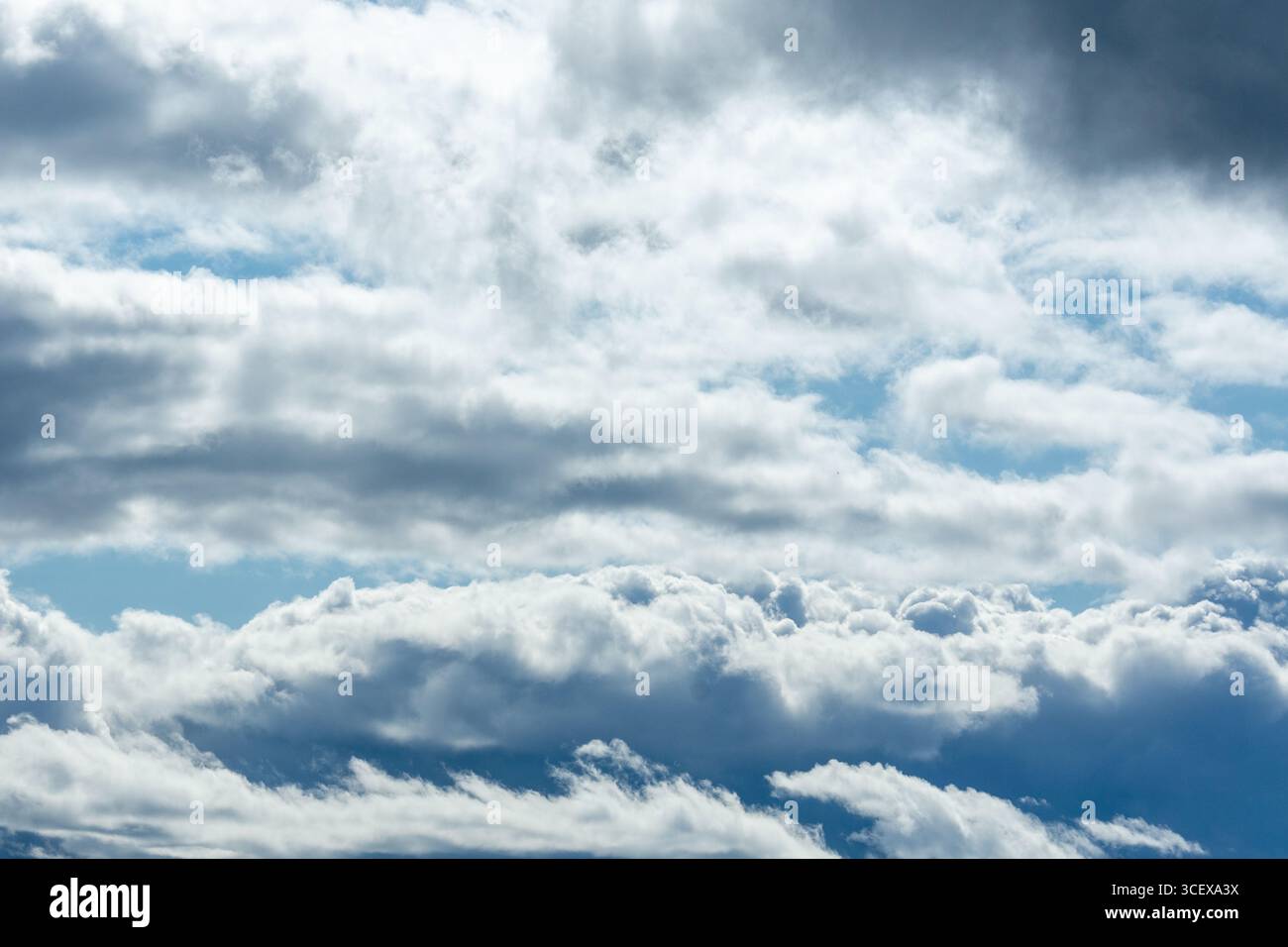 Cumulus and Stratus Clouds Layered in Dramatic Blue Sky with Light and Shadows. Stock Photo