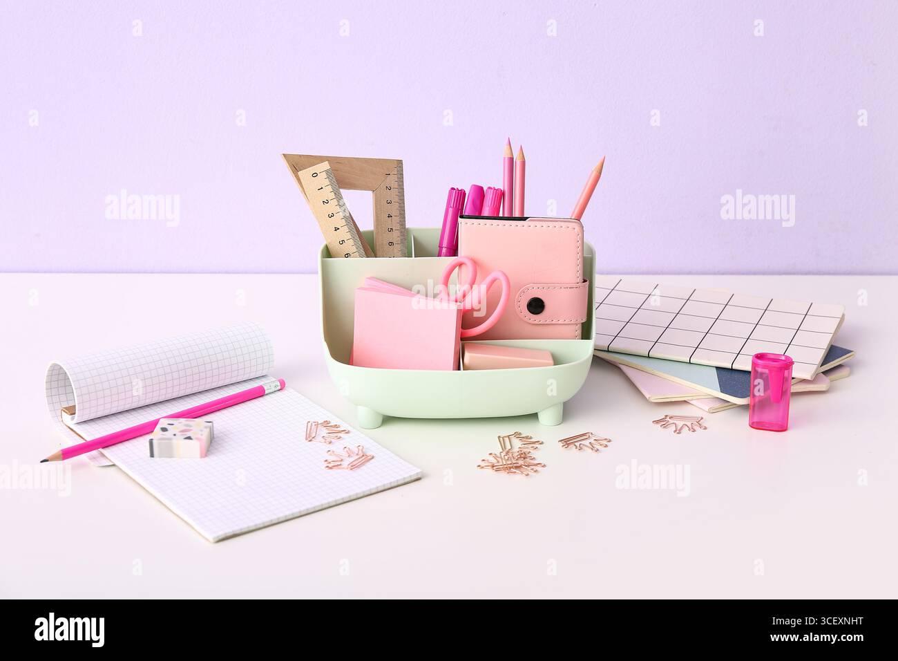 Holder with different stationery and notebooks on light desk Stock Photo