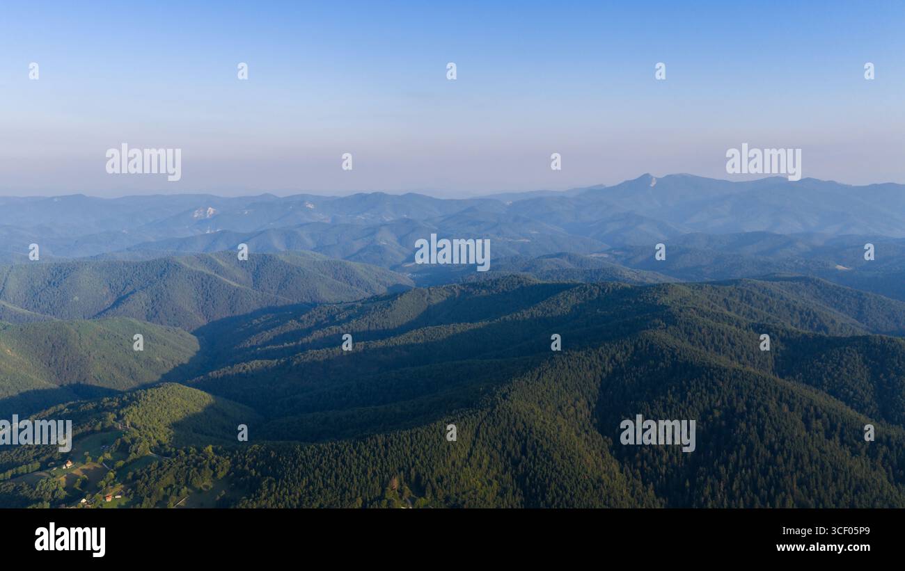 Endless ridgelines unfold under blue skies, offering a glimpse into pure, untouched mountain wilderness Stock Photo