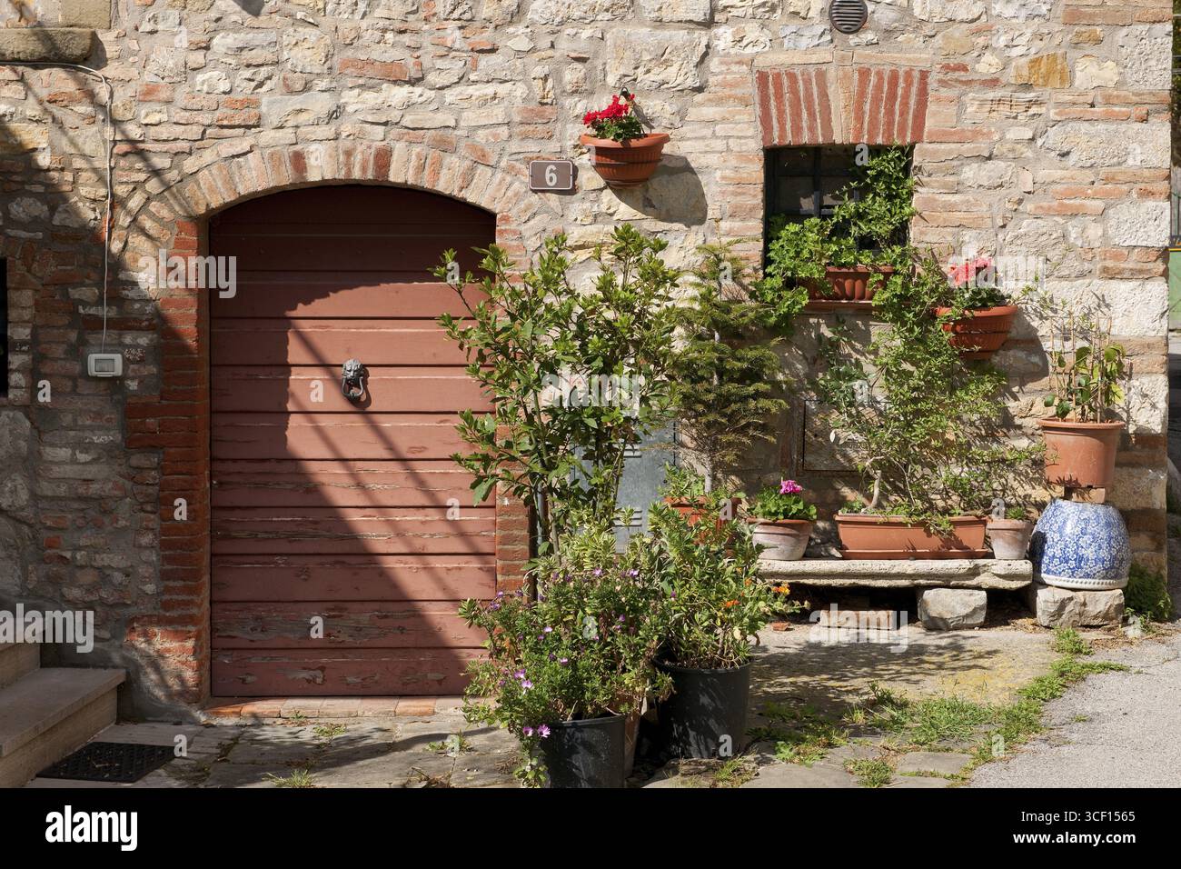Tuscany country house detail with flower bench planter next to old wooden door quarry stone wall, Tuscany, Italy Stock Photo