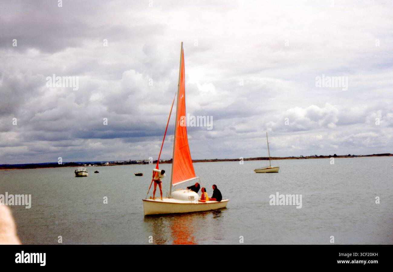 Sailing dinghy with orange sail in the Gulf of Morbihan, Brittany, France, August 1963. Stock Photo