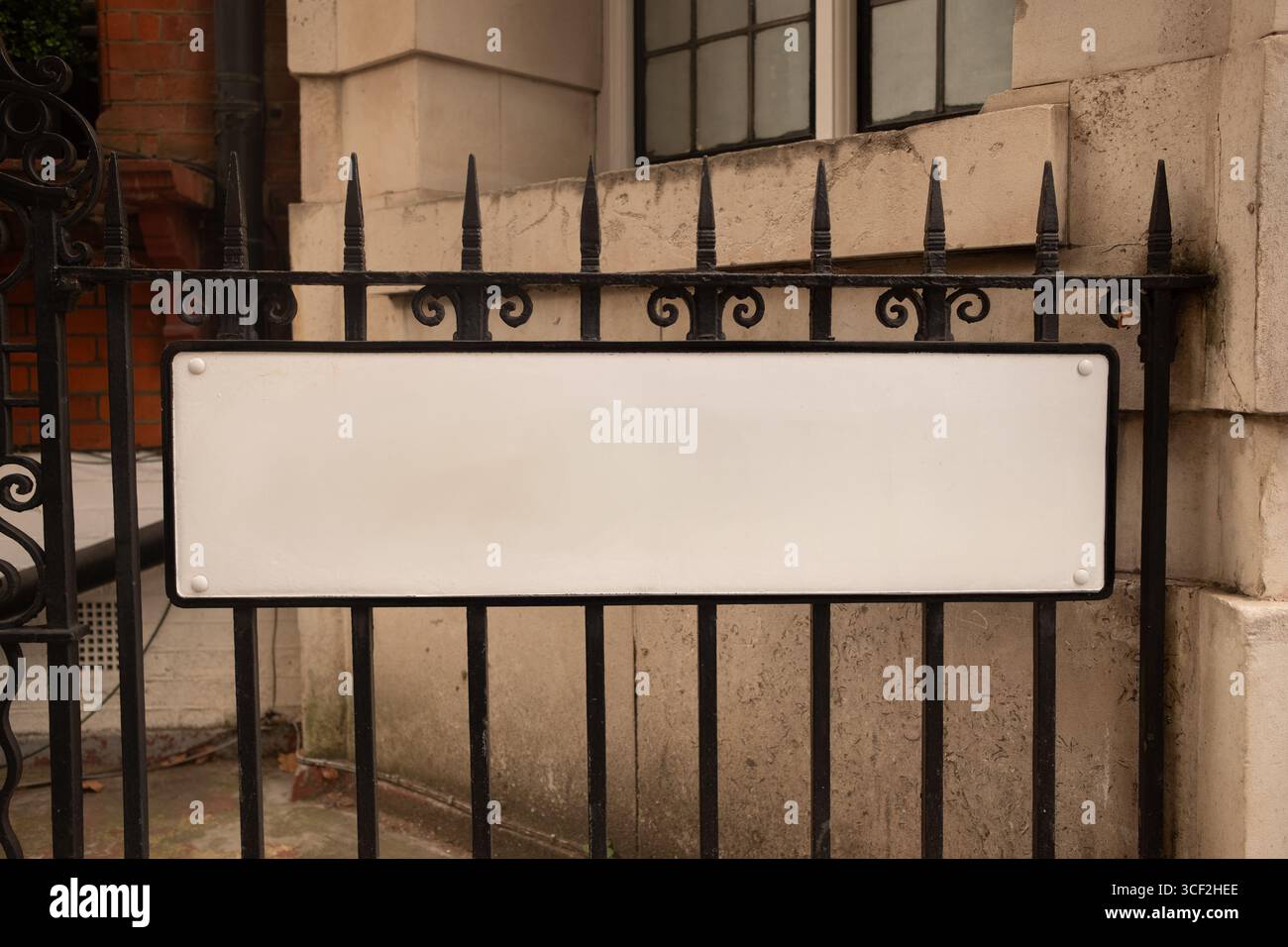 Blank white sign on black cast iron railings in urban building setting Stock Photo