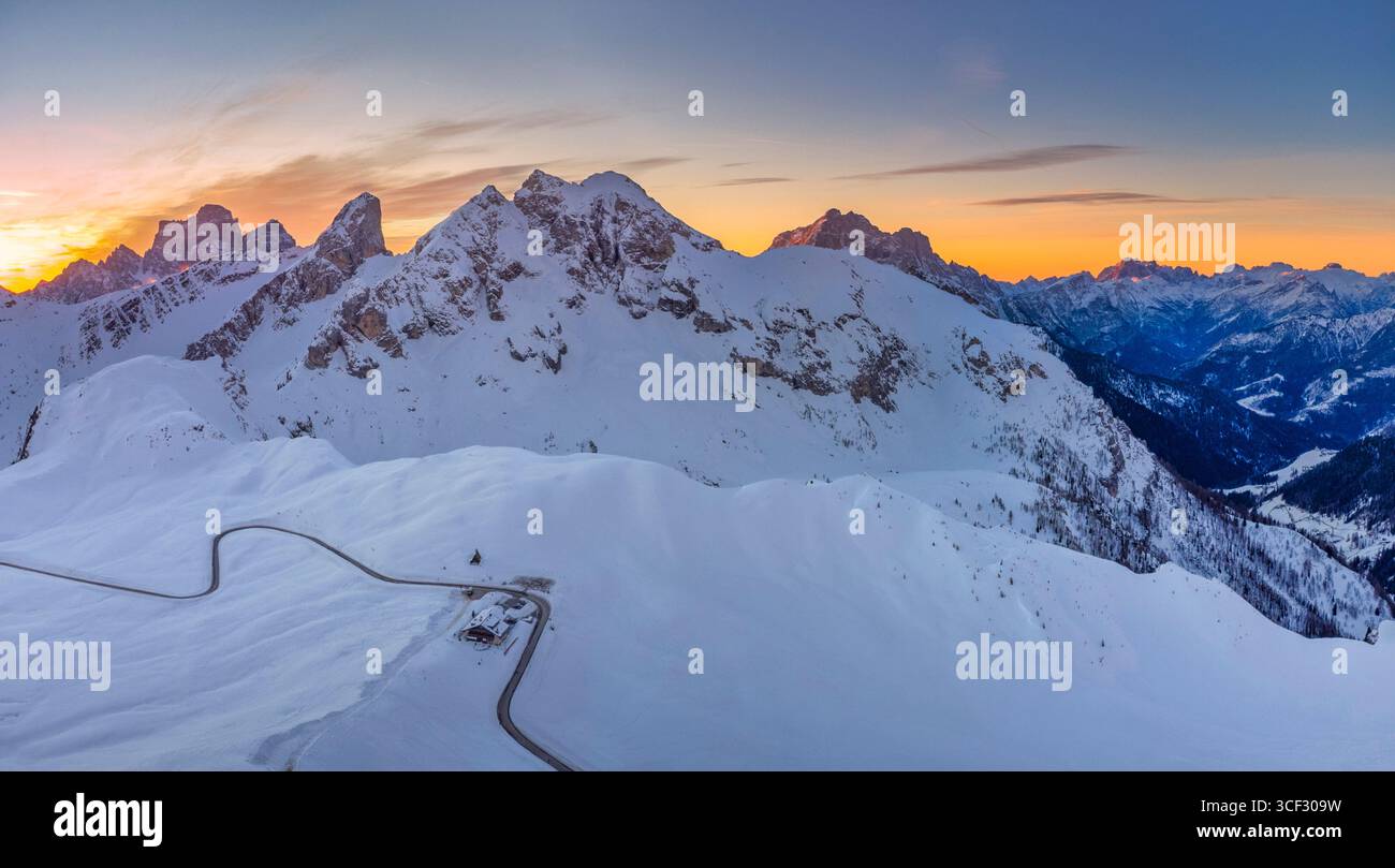Aerial winter view over Passo Giau with Monte Cernera in the center, Monte Pelmo in the background to the left, and Monte Civetta to the right. The winding pass road and a mountain refuge are visible among the snow-covered alpine slopes. Dolomites, Colle Santa Lucia municipality, Belluno province, Veneto region, Italy Stock Photo