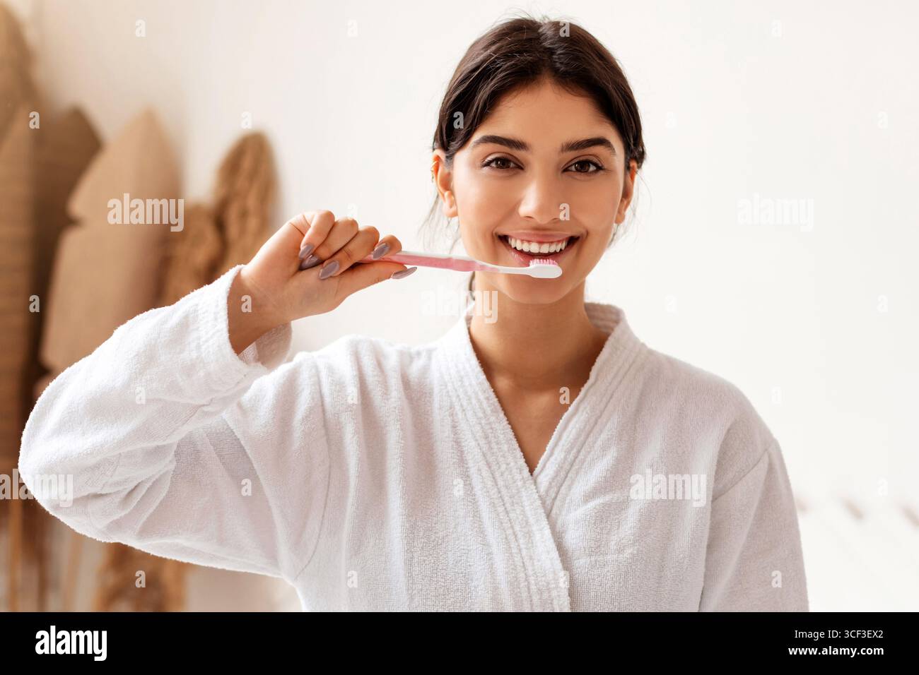 Woman Brushing Teeth With Toothbrush Smiling Standing In Bathroom Indoor Stock Photo
