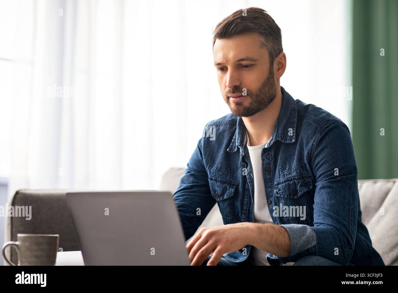 Middle-aged businessman working from home, using laptop Stock Photo