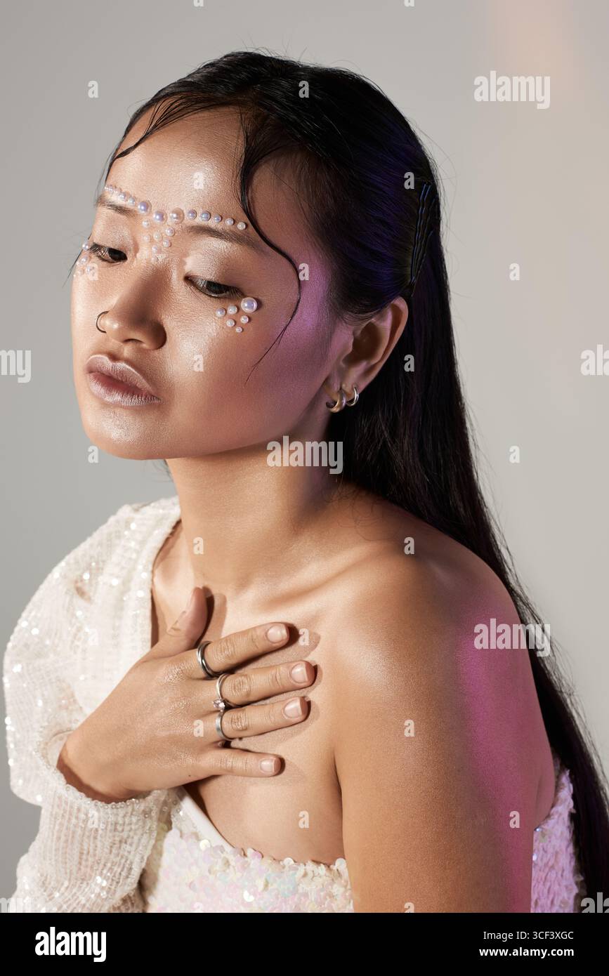 A young Asian woman poses artistically with stunning makeup and pearls on her face. Stock Photo