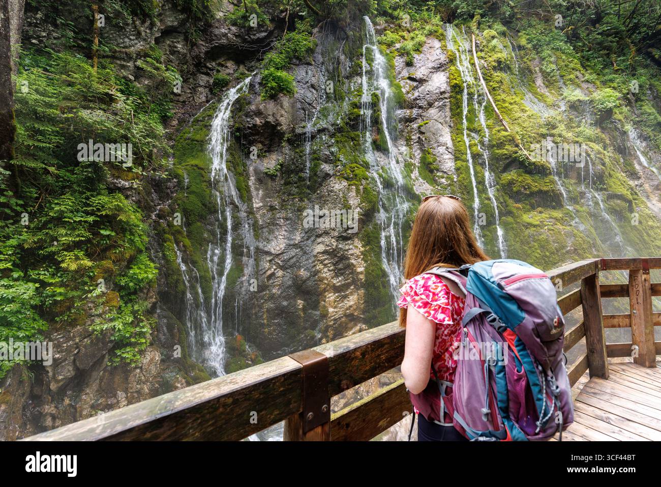 27 June 2025, Bavaria, Ramsau: A young woman stands with a view of ...