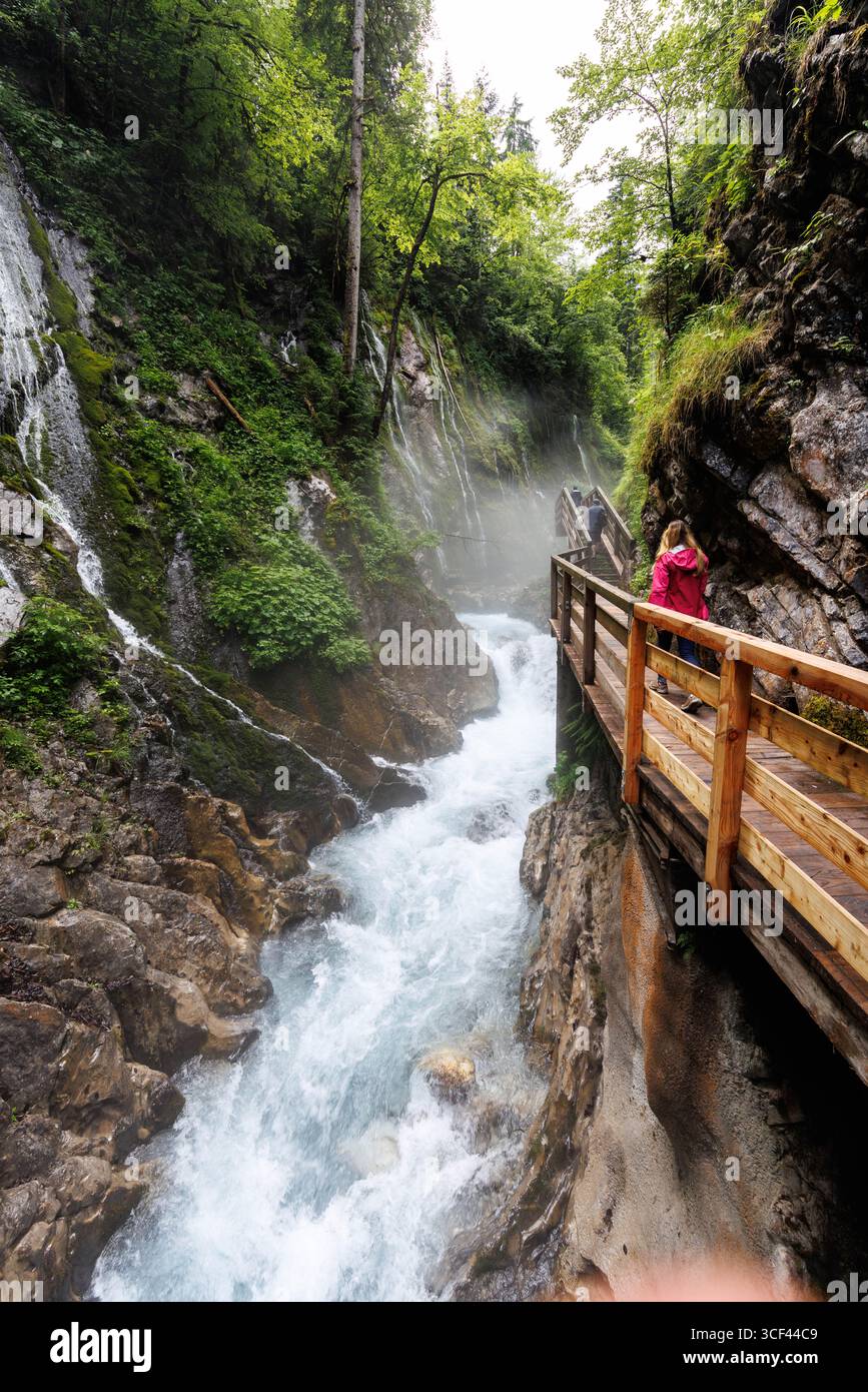 27 June 2025, Bavaria, Ramsau: A young woman stands with a view of ...