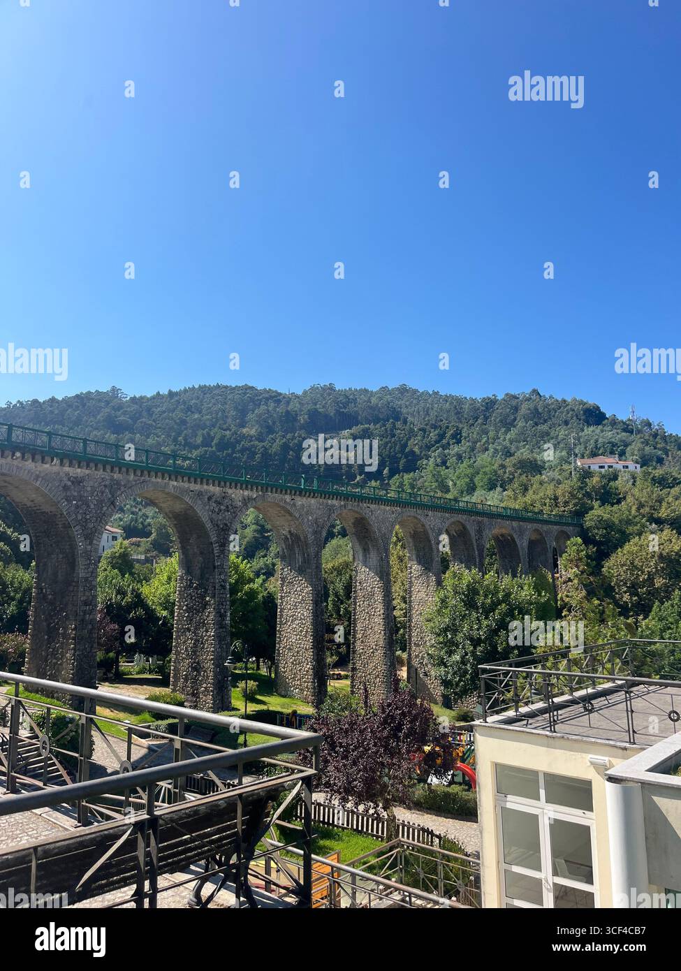 Historic stone railway viaduct in Vouzela, Portugal, with arches spanning across a scenic green valley. - Smartphone Captured Stock Image