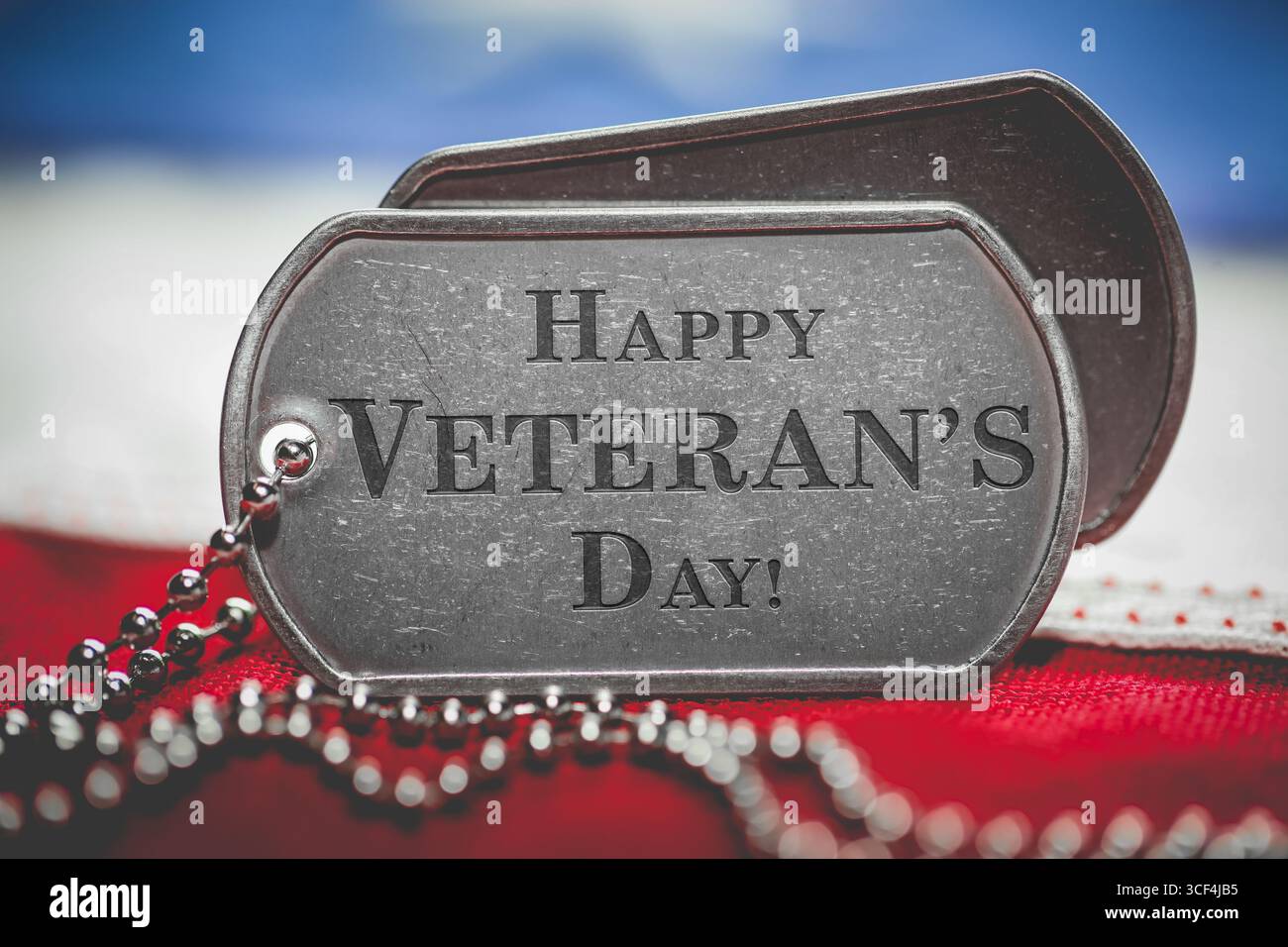 Worn US American dog tags on USA flag with Happy Veteran's Day engraved ...