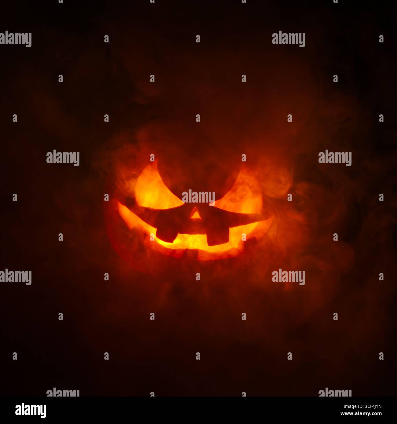 Spooky carved Jack o Lantern glowing a fiery red with thick smoke ...