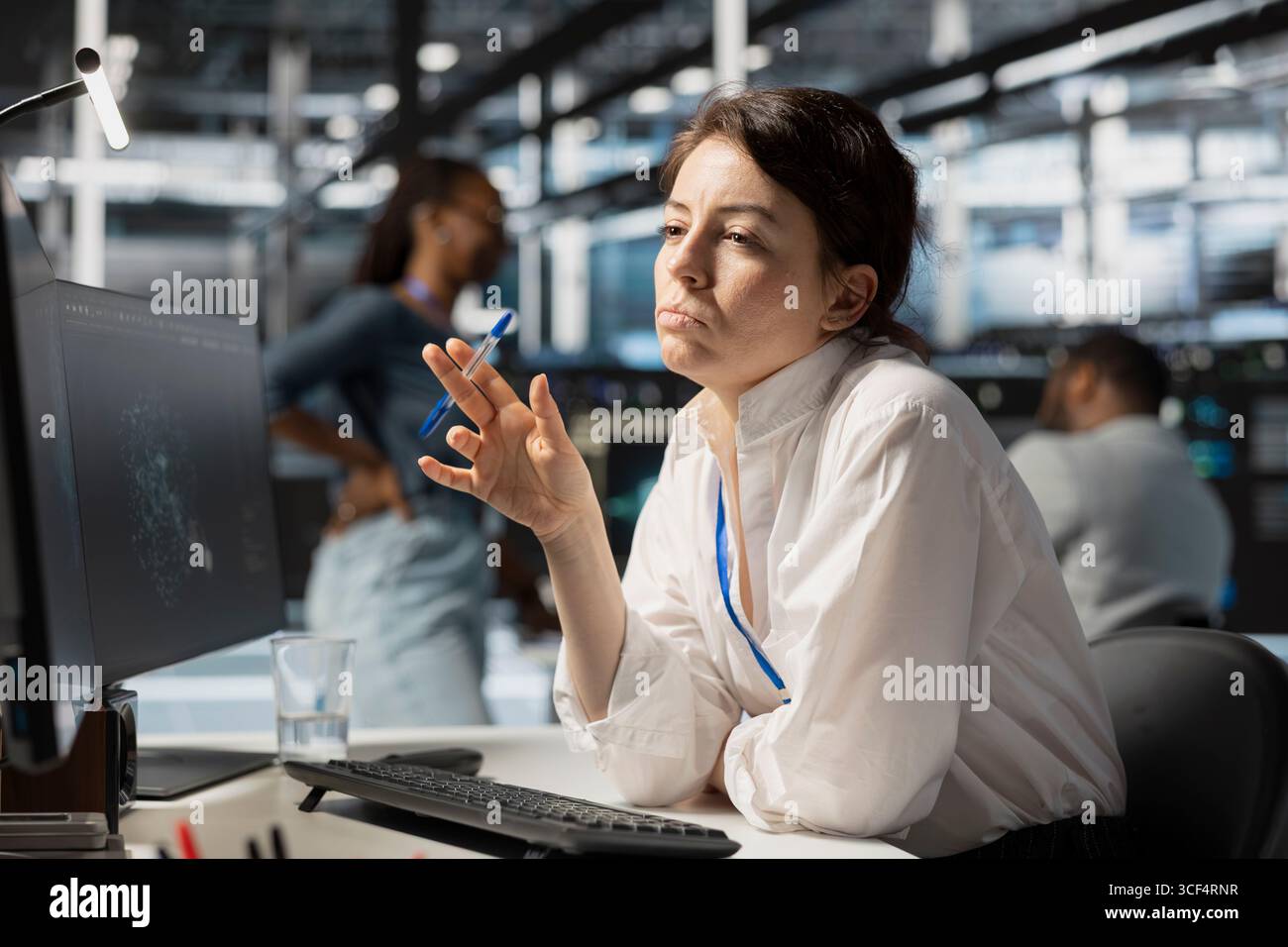 Pensive server hub engineer looking at data visualization on PC, thinking how to fix performance issues. Data center worker looks at analysis graph, brainstorming how to repair hardware failures Stock Photo