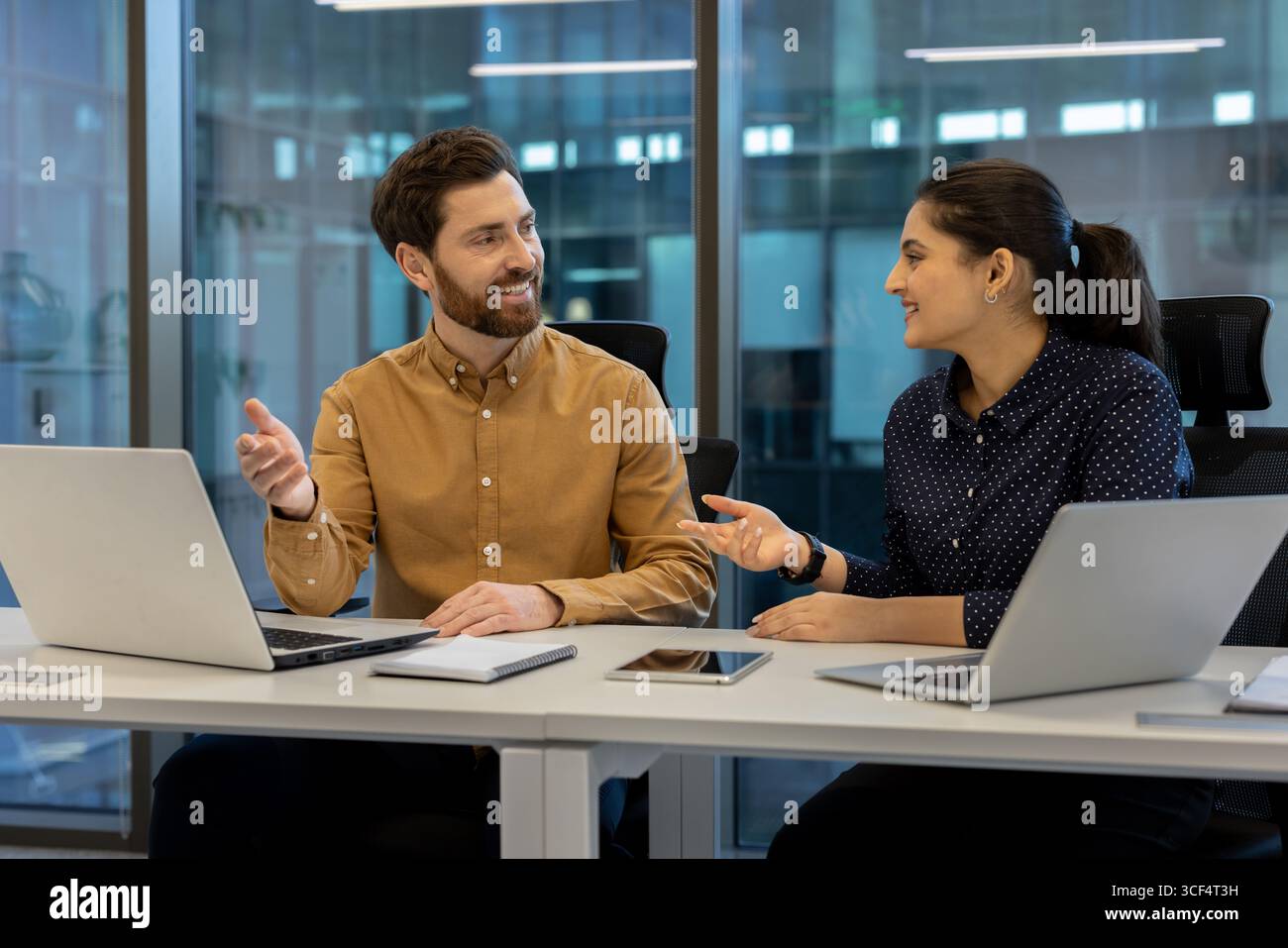 Professional collaboration between two coworkers in a modern workspace setting. Stock Photo