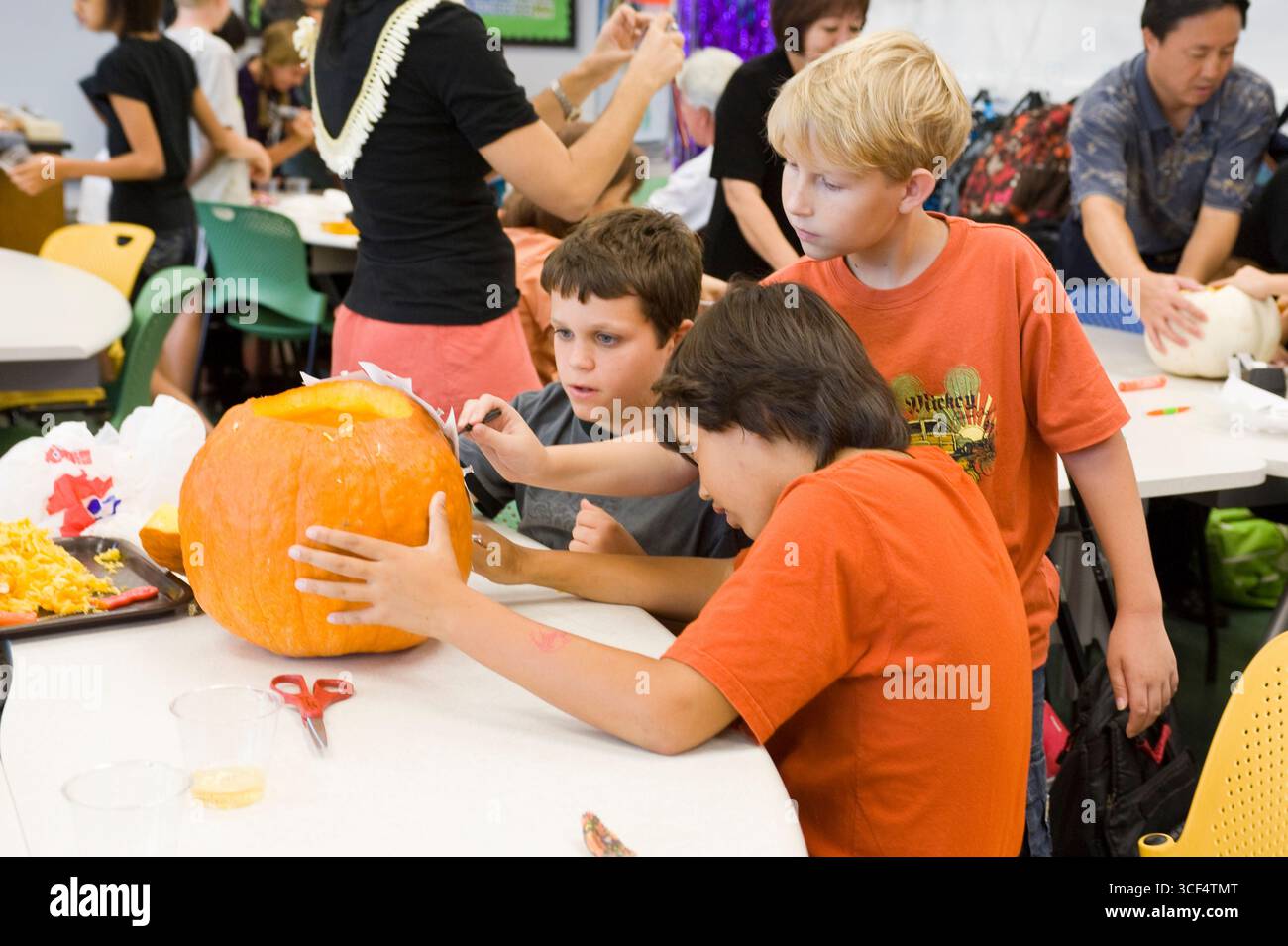 Three Boys Working On Carving A Jack O Lantern For Halloween In