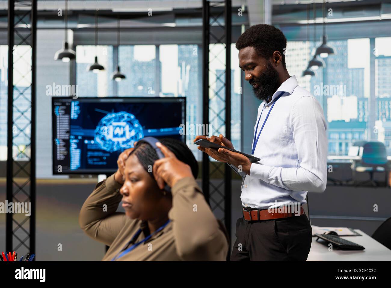 Computer scientist utilizing artificial intelligence to optimize performance using tablet. African american engineer in office training machine learning models with device Stock Photo