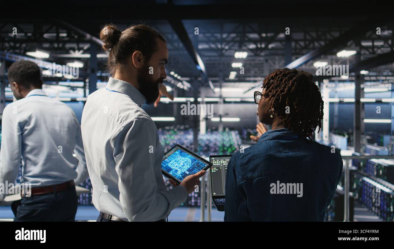 Data center system administrators performing maintenance on supercomputers used for AI. Engineering team managing server hub rigs used for deep learning training, Stock Photo