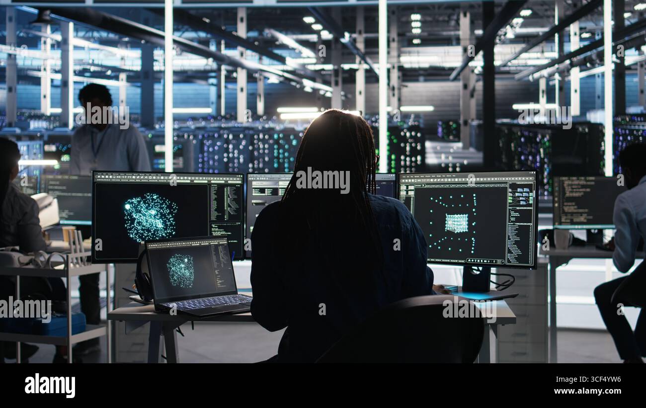 Data center programmer entering office uses node tree program to identify equipment performance issues. Server hub worker sitting at desk, reviewing data analysis graph to minimize failures, camera A Stock Photo